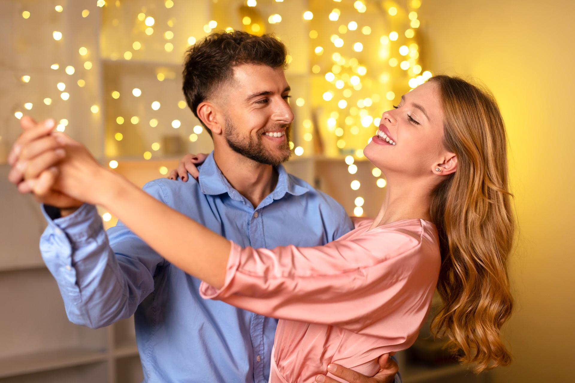 Couple dancing joyfully in a romantic, light-filled room