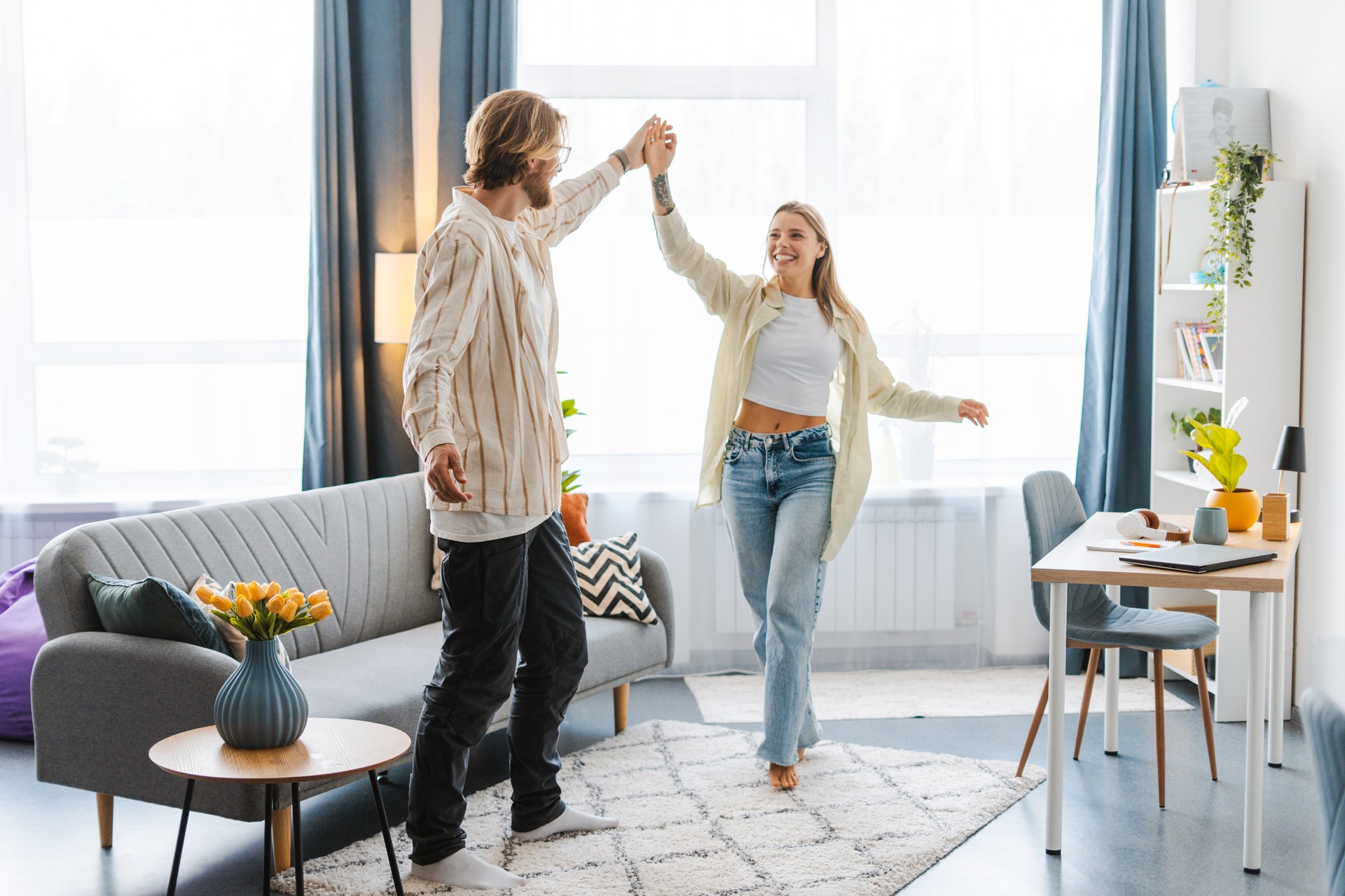 Happy young couple dancing and having fun together in their modern apartment